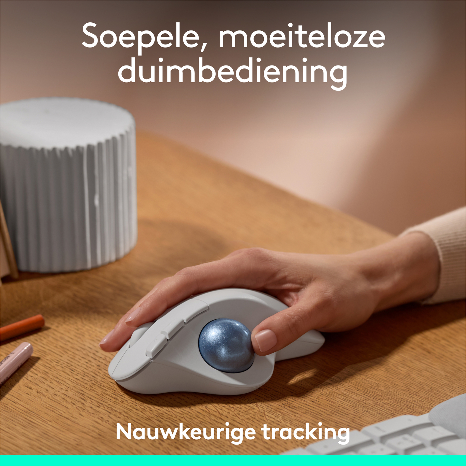 Een hand die een witte muis met een blauwe trackball op een houten bureau gebruikt.