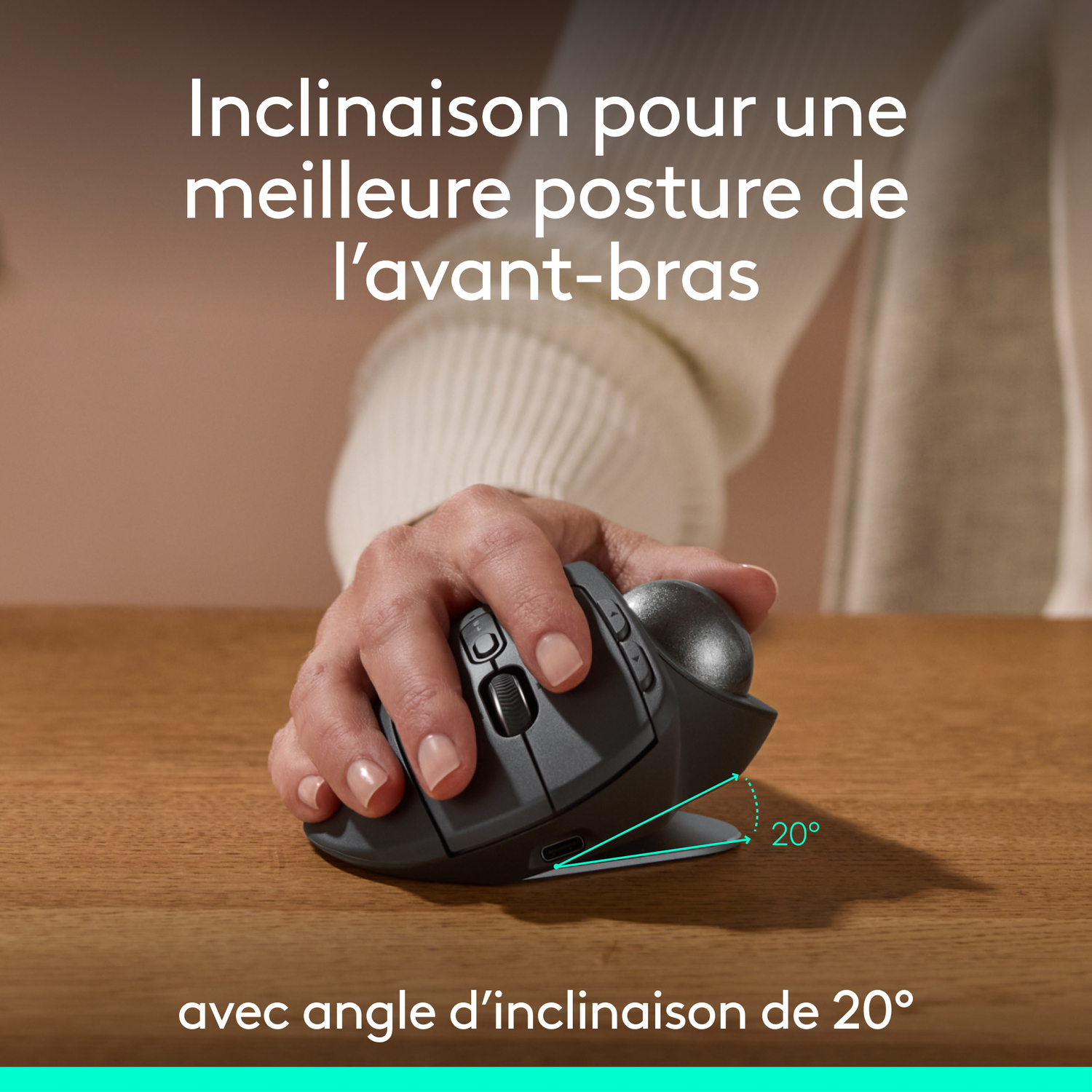 Une main tenant une souris trackball noire, avec une inclinaison de 20 degrés et du texte en français.