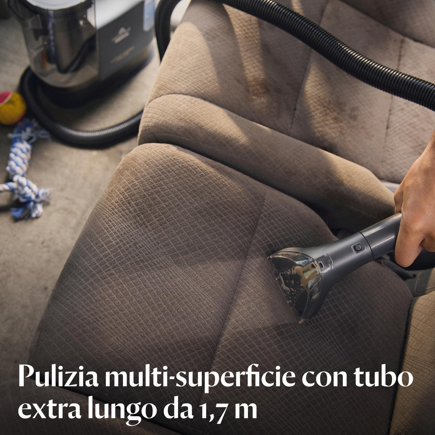 Una persona sta pulendo un sedile per auto con un aspirapolvere.