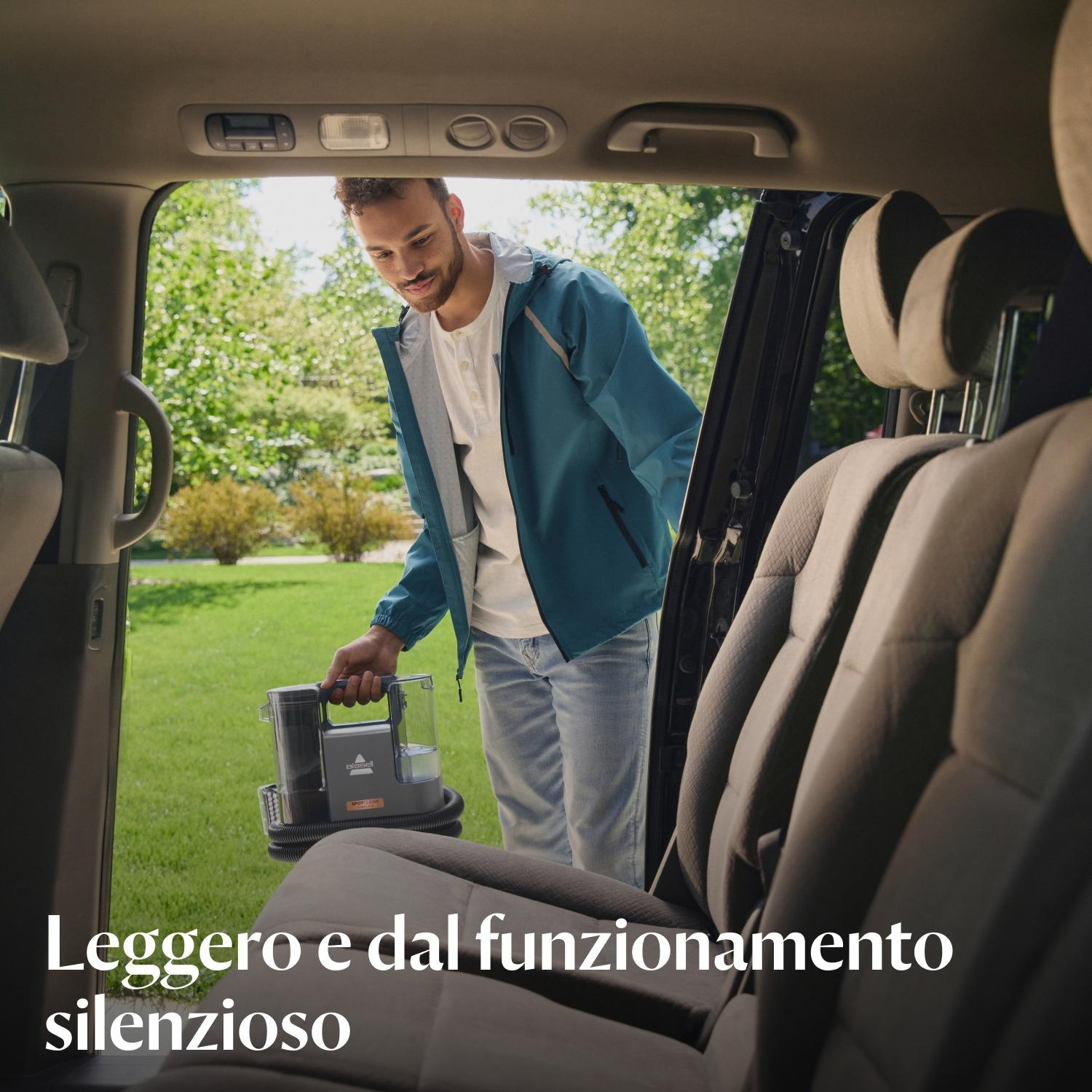Uomo che tiene un dispositivo di pulizia all'interno di un'auto. L'interno dell'auto è visibile.