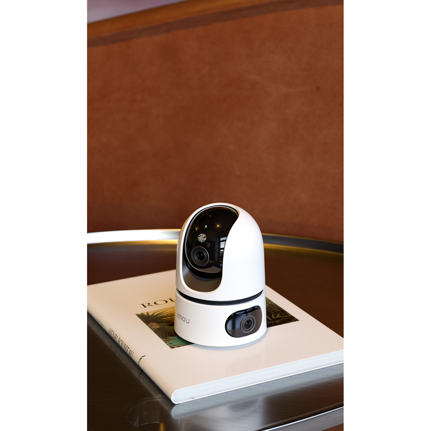 White security camera on a table, next to a book, brown background.