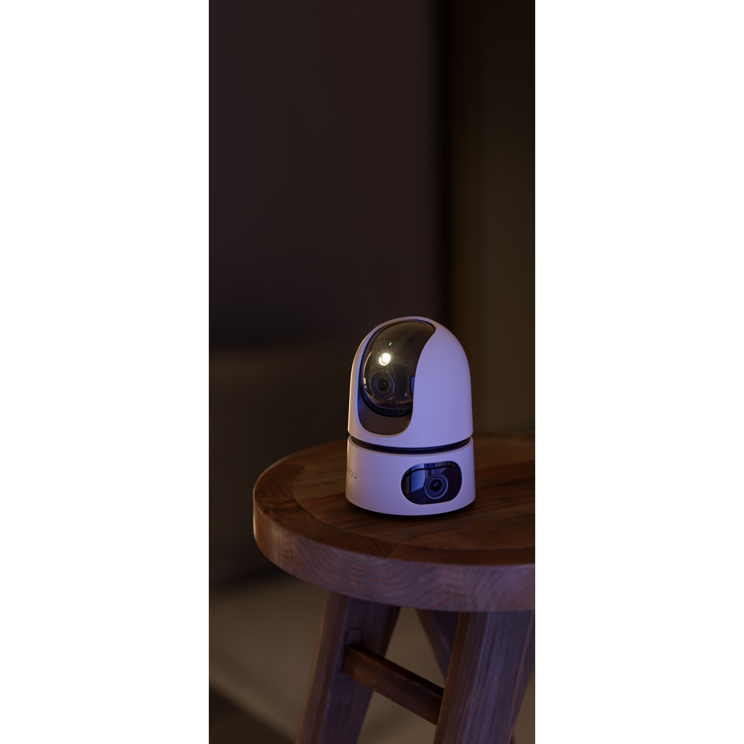 A white and pink security camera on a wooden stool, against a dark background.