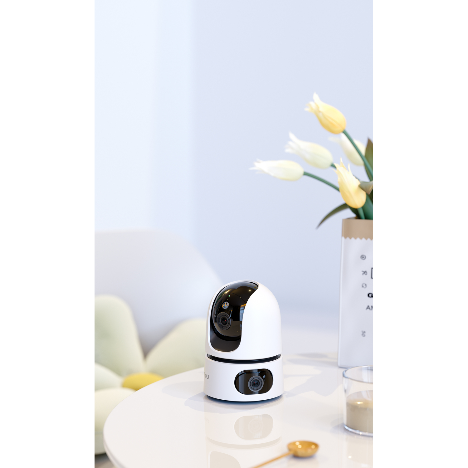 A white and black security camera on a white table with a vase of flowers.