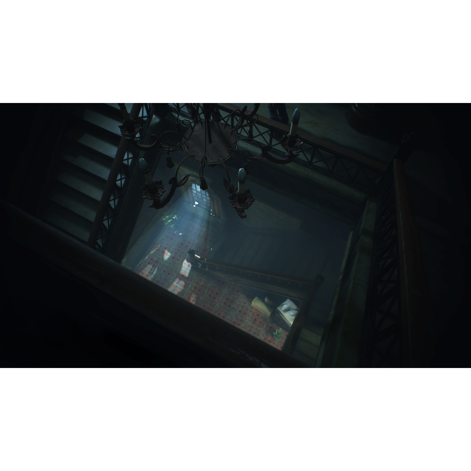 Dark interior, high-angle shot down a staircase with a chandelier.