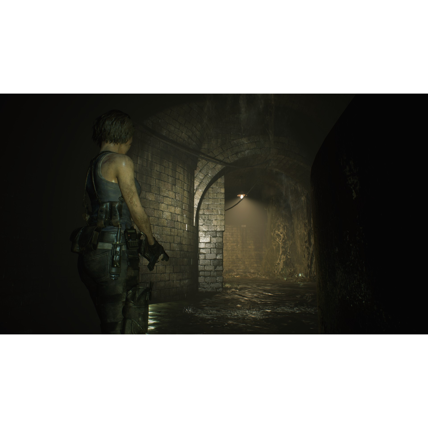 A woman with a gun stands in a dark, brick-walled tunnel. The scene is dim and ominous.