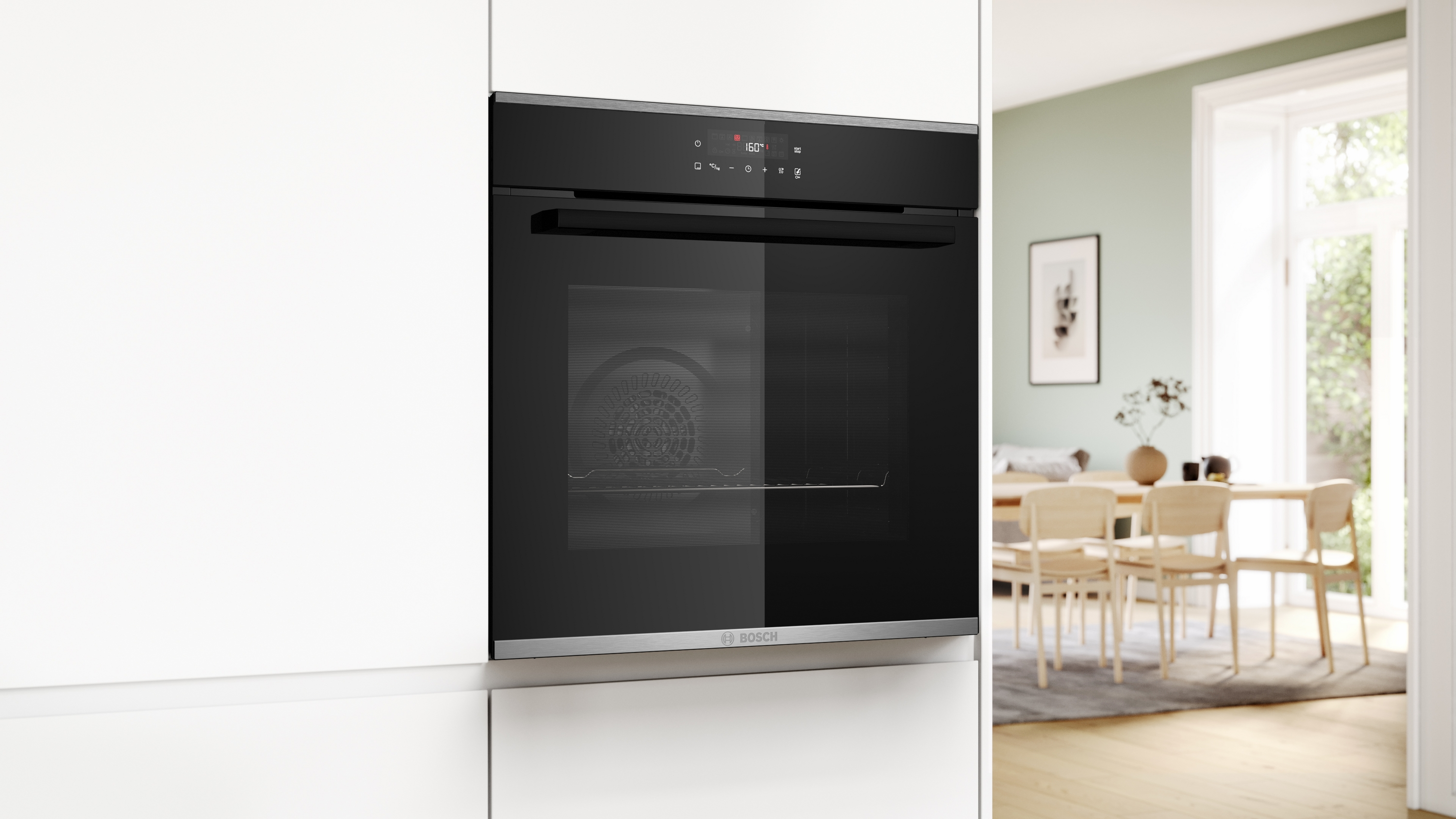 Ein schwarzer Ofen ist in eine weiße Küche eingebaut. Es gibt einen Blick in ein Esszimmer mit Tisch und Stühlen.