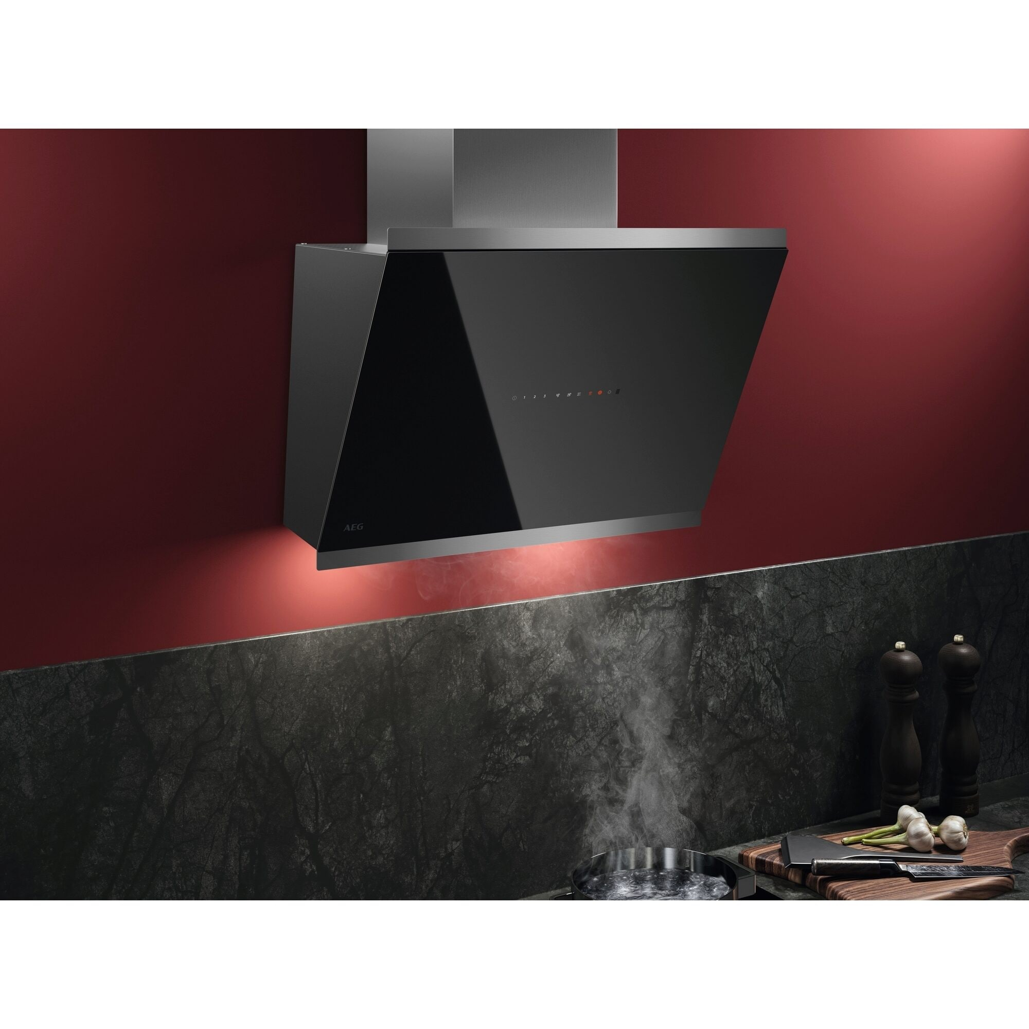 Schwarze Küchenhaube über einem Herd. Rote Wand, dunkle Theke, Dampf.