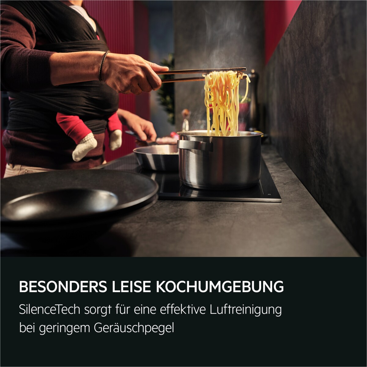 Person kocht Nudeln in einem Topf. Ein Baby ist in einer Trage. Text: 'BESONDERS LEISE KOCHUMGEBUNG'.