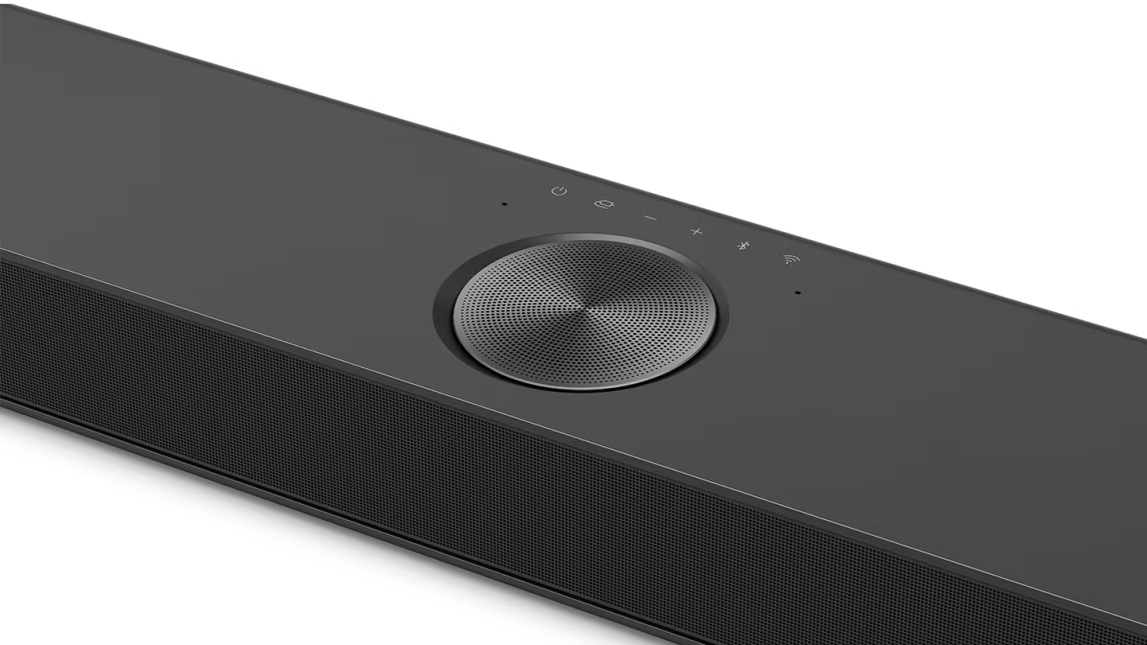 Czarny soundbar na białym tle, z przyciskami i maskownicą głośnika.