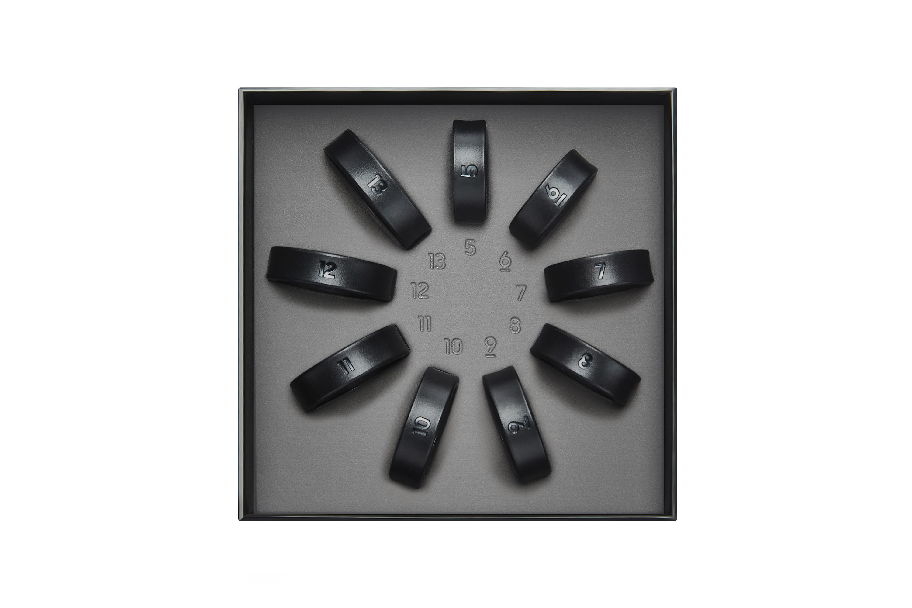 Okrągłe czarne skórzane bransoletki z numerami w szarej tacy.