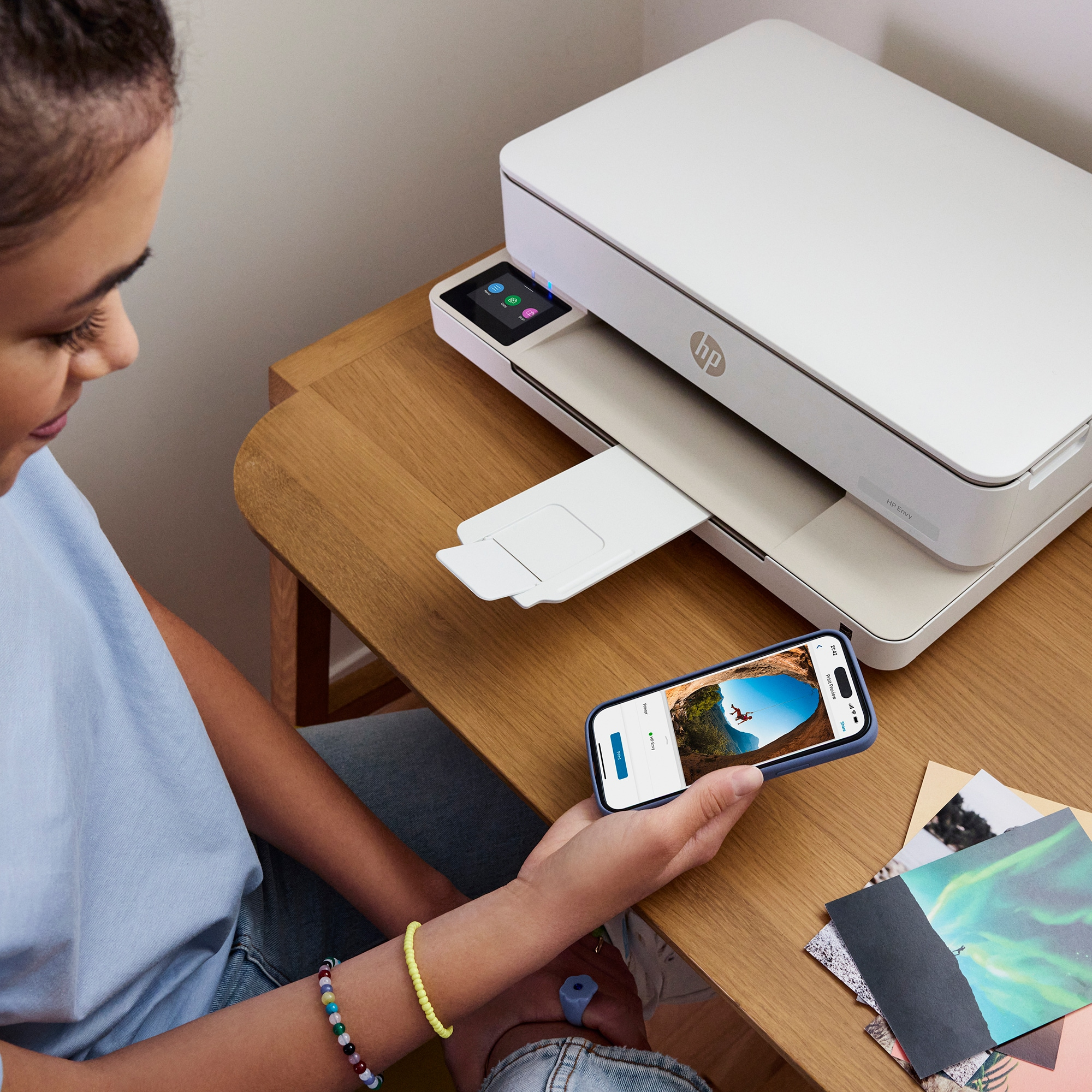 Eine Frau hält ein Smartphone, während ein weißer Drucker druckt. Das Telefon zeigt ein Foto.