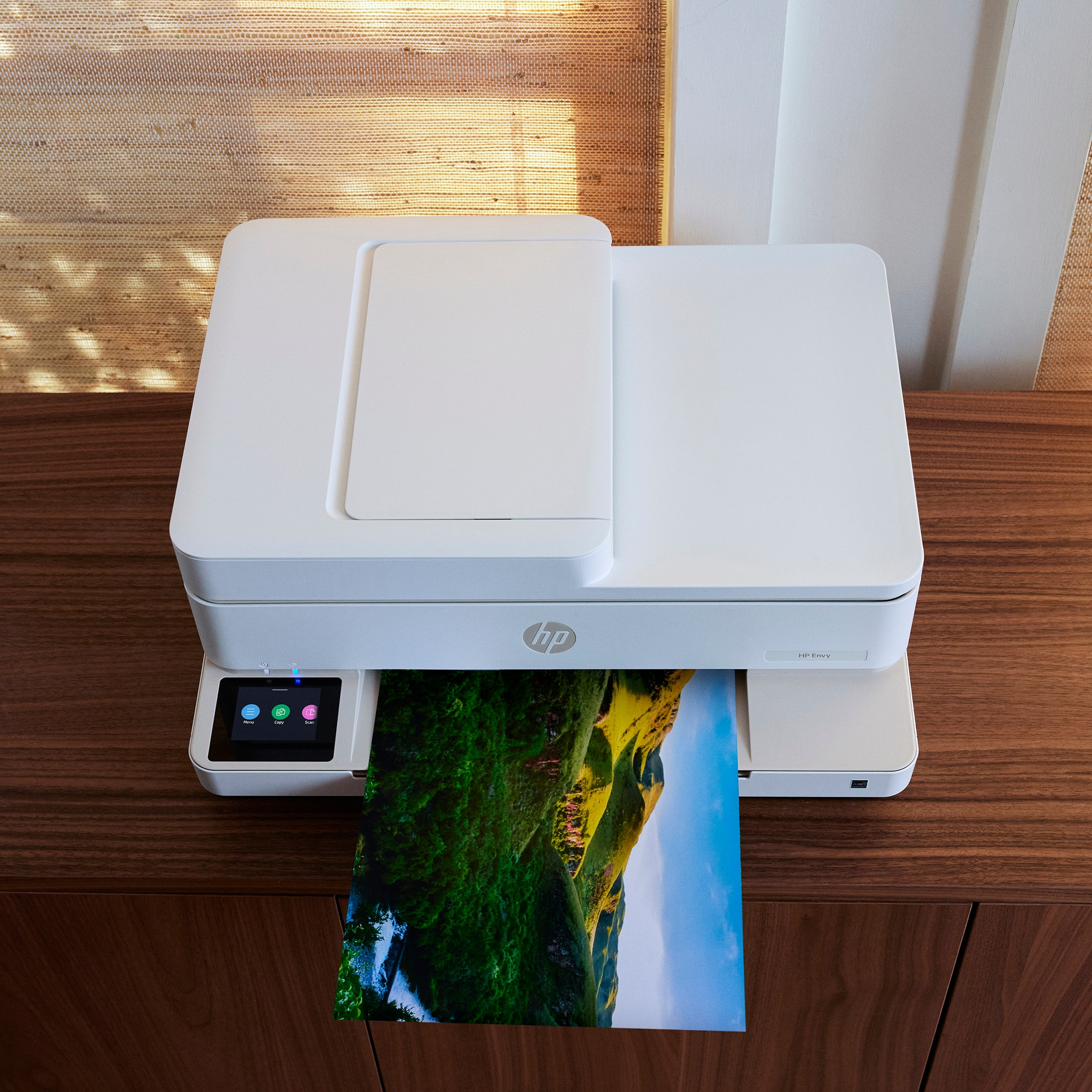 White printer printing a landscape image on a wooden table.