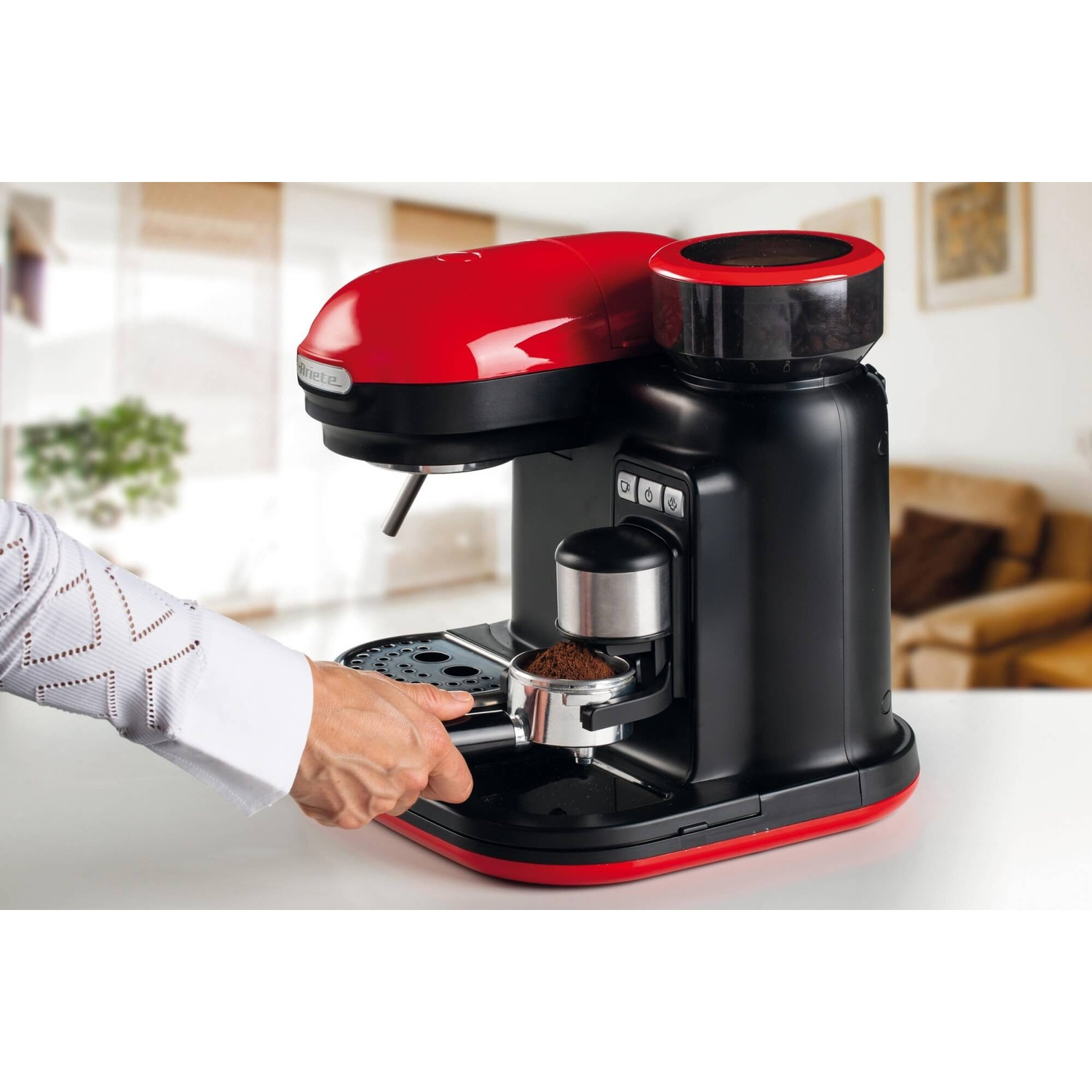 Una persona aggiunge caffè macinato a una macchina per caffè espresso rossa e nera.