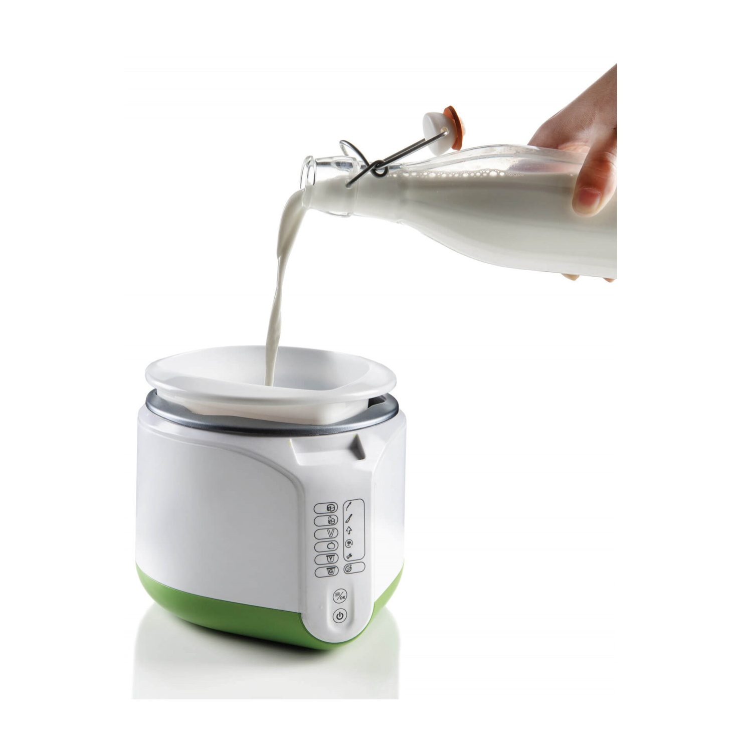 Latte versato da una bottiglia in un dispositivo per latte bianco e verde. Sfondo bianco.