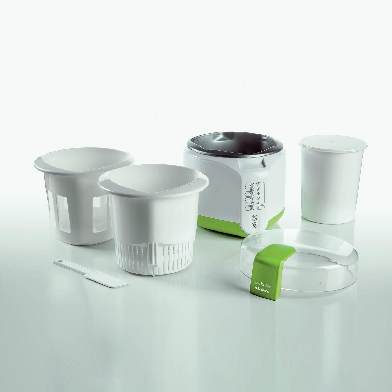 Elettrodomestico da cucina bianco e verde con contenitori e una piccola spatola su una superficie bianca.