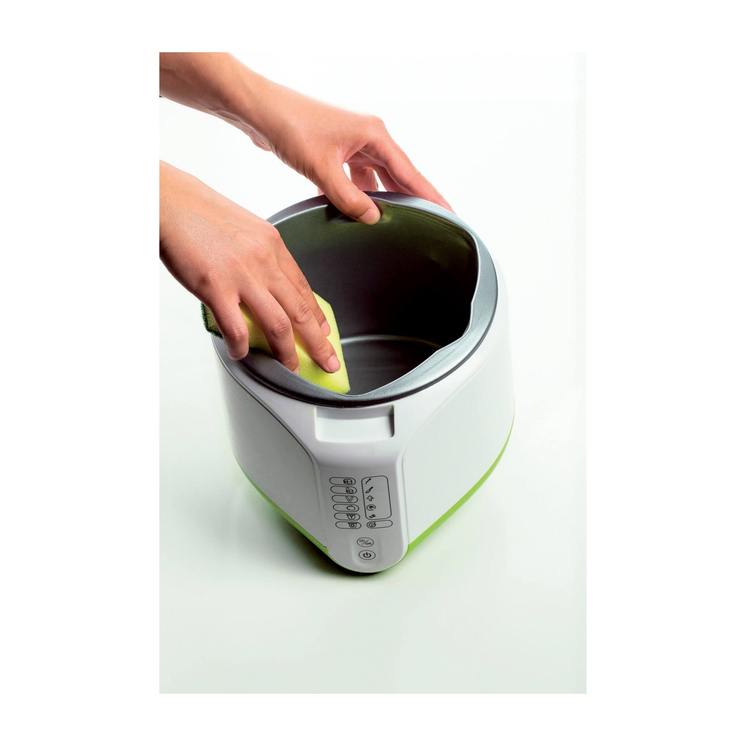 Mani che puliscono un elettrodomestico bianco e verde con una spugna gialla.