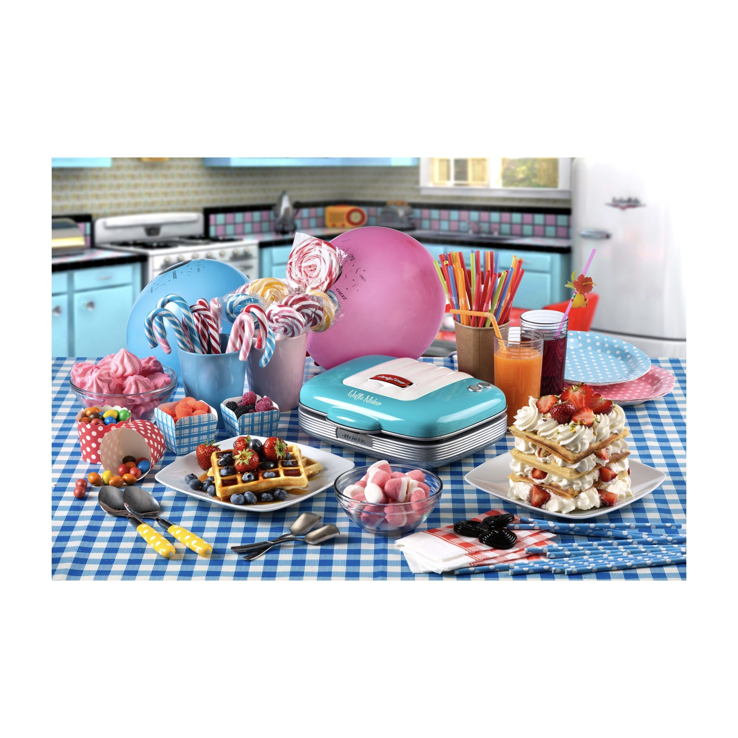 Tavolo con dolci: waffle, caramelle, bevande, palloncini rosa e blu e una macchina per waffle.