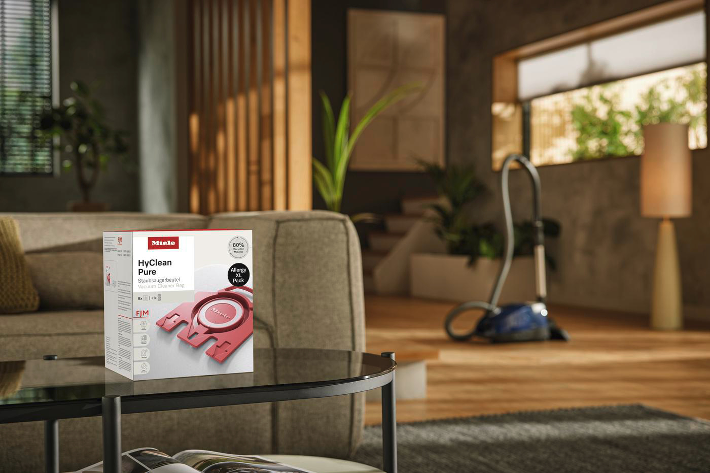Wohnzimmer mit Sofa, Staubsaugerbox auf einem Tisch und Staubsauger.