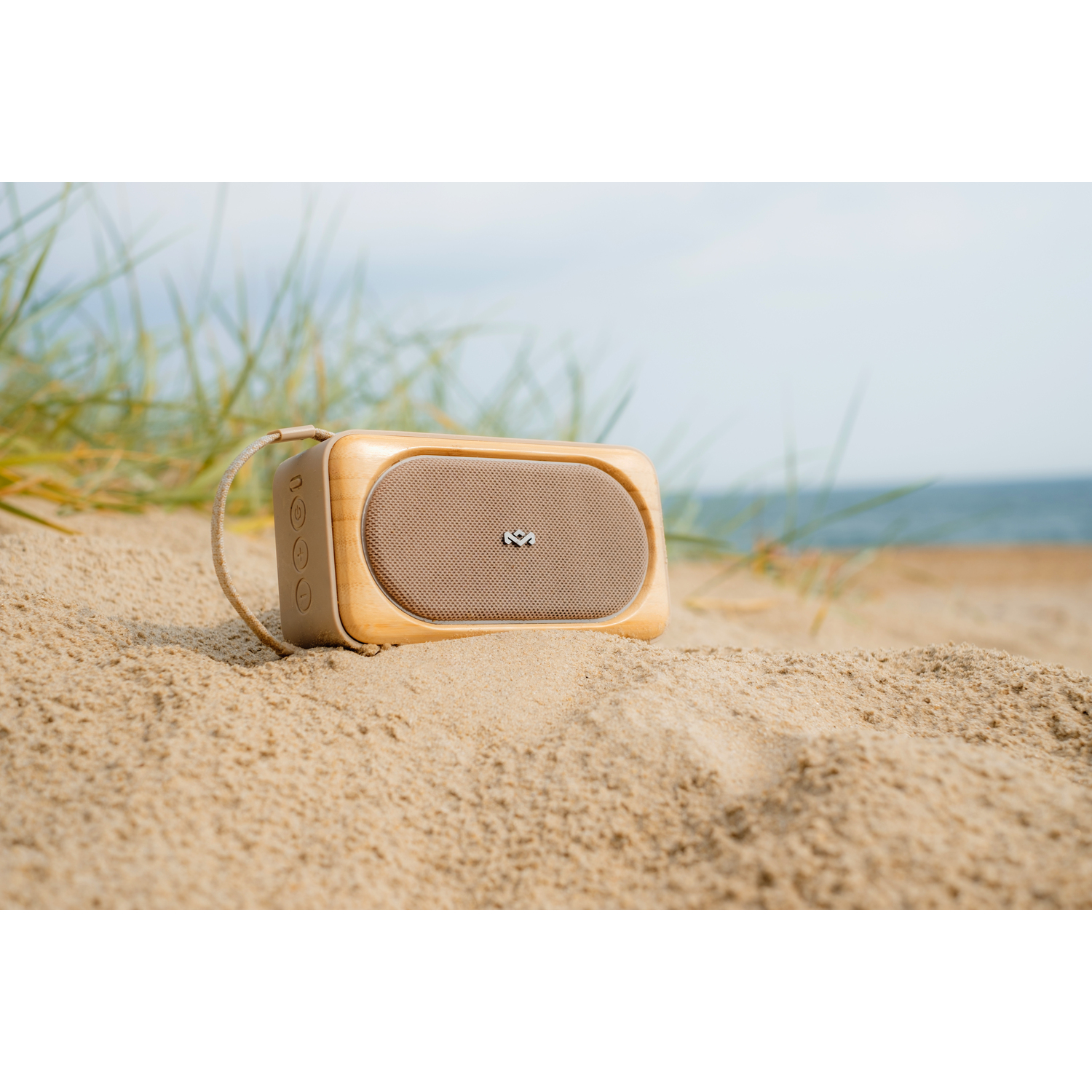 Een houten luidspreker staat op het zand bij het strand.