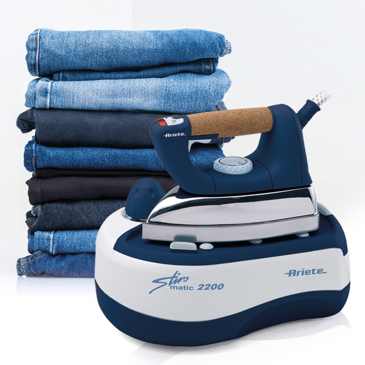 Un ferro da stiro blu e bianco con una pila di jeans accanto, su una superficie bianca.