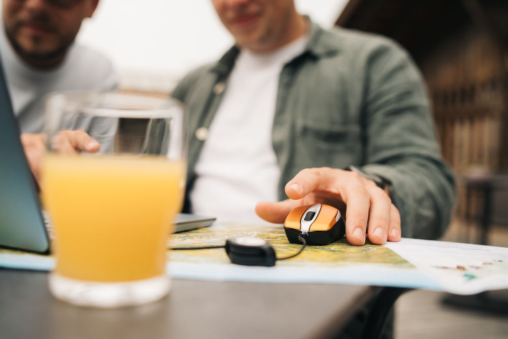 Dwóch mężczyzn patrzy na mapę, jeden używa myszy na stole.