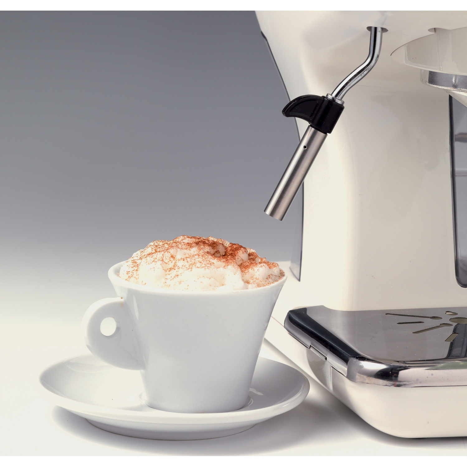 Macchina per espresso bianca che eroga cappuccino con cacao. Tazza su piattino bianco.