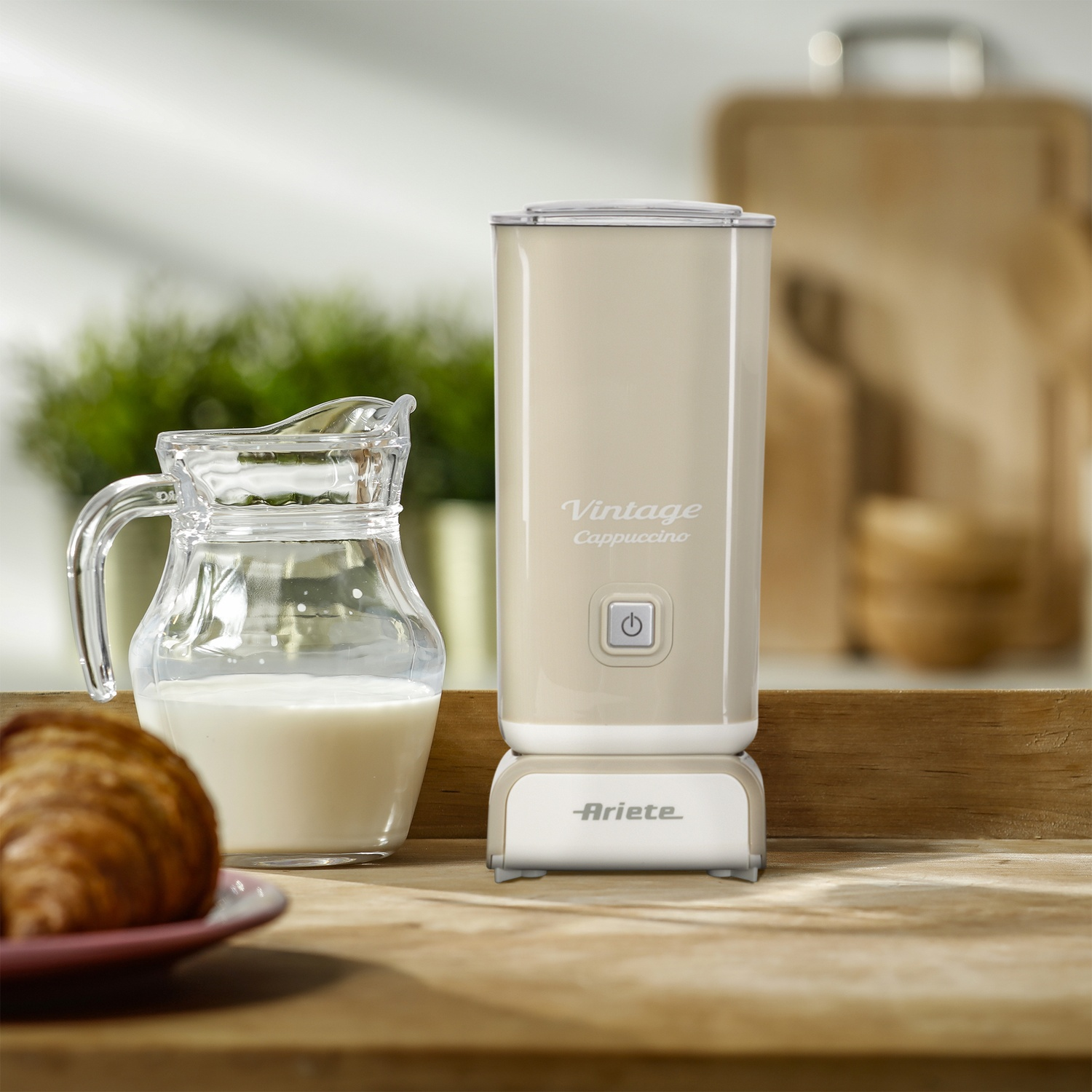 Una macchina per cappuccino vintage con una brocca per il latte e un croissant accanto, su una superficie di legno.