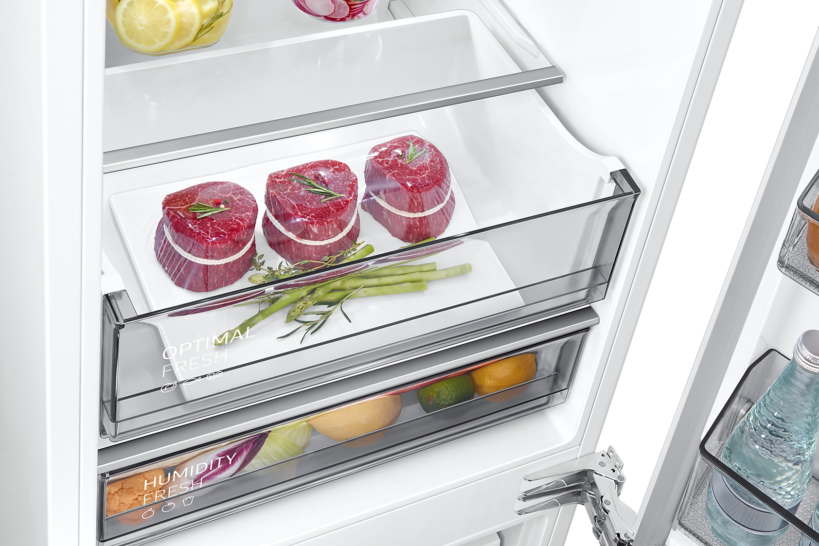 Offener Kühlschrank mit verpacktem Fleisch, Spargel und Obst in Schubladen.