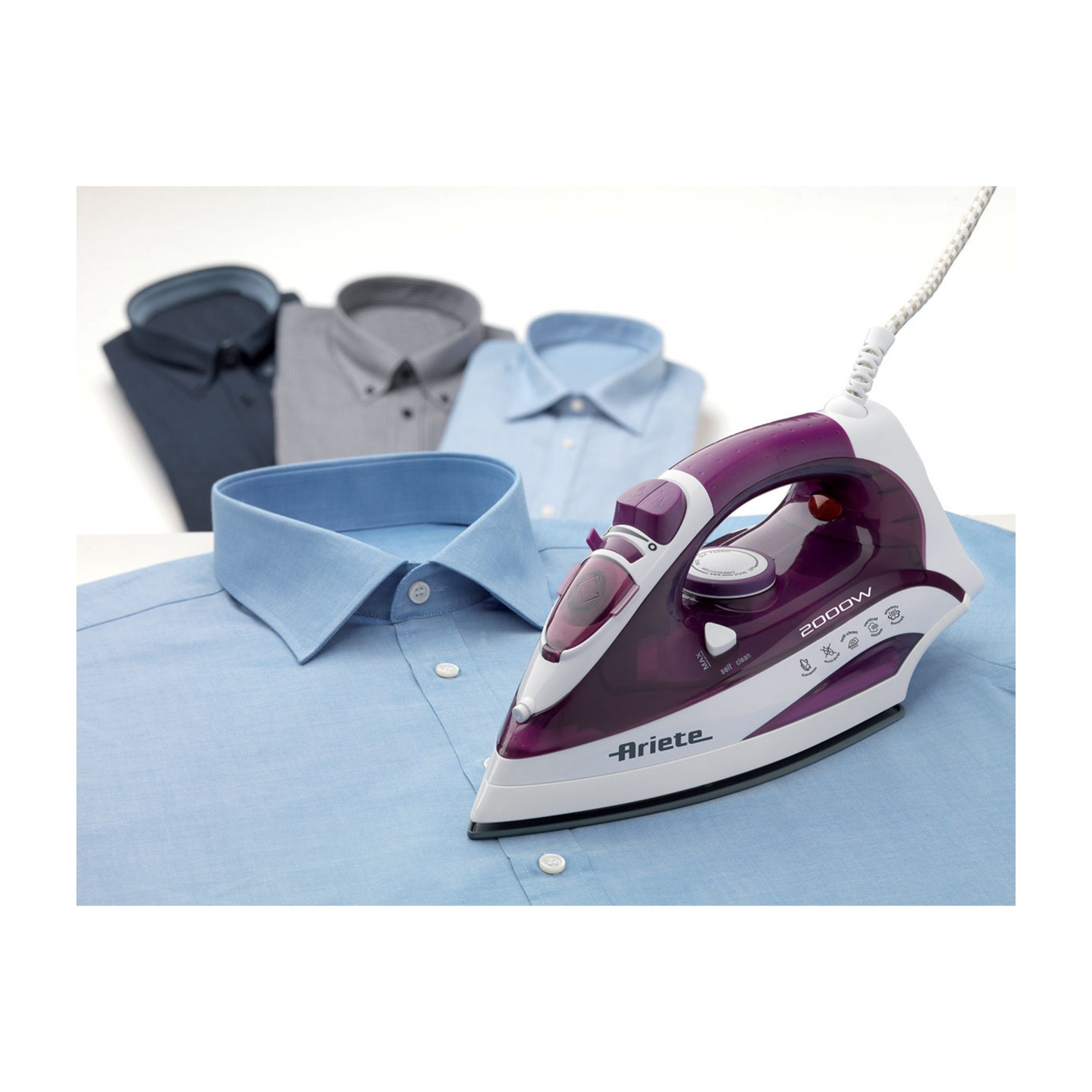 Ferro da stiro su camicia blu con altre camicie sullo sfondo. Ferro viola e bianco.