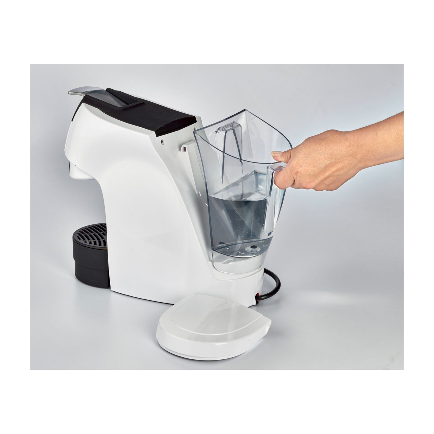 Macchina da caffè bianca e nera. Mano che tiene un contenitore d'acqua trasparente.