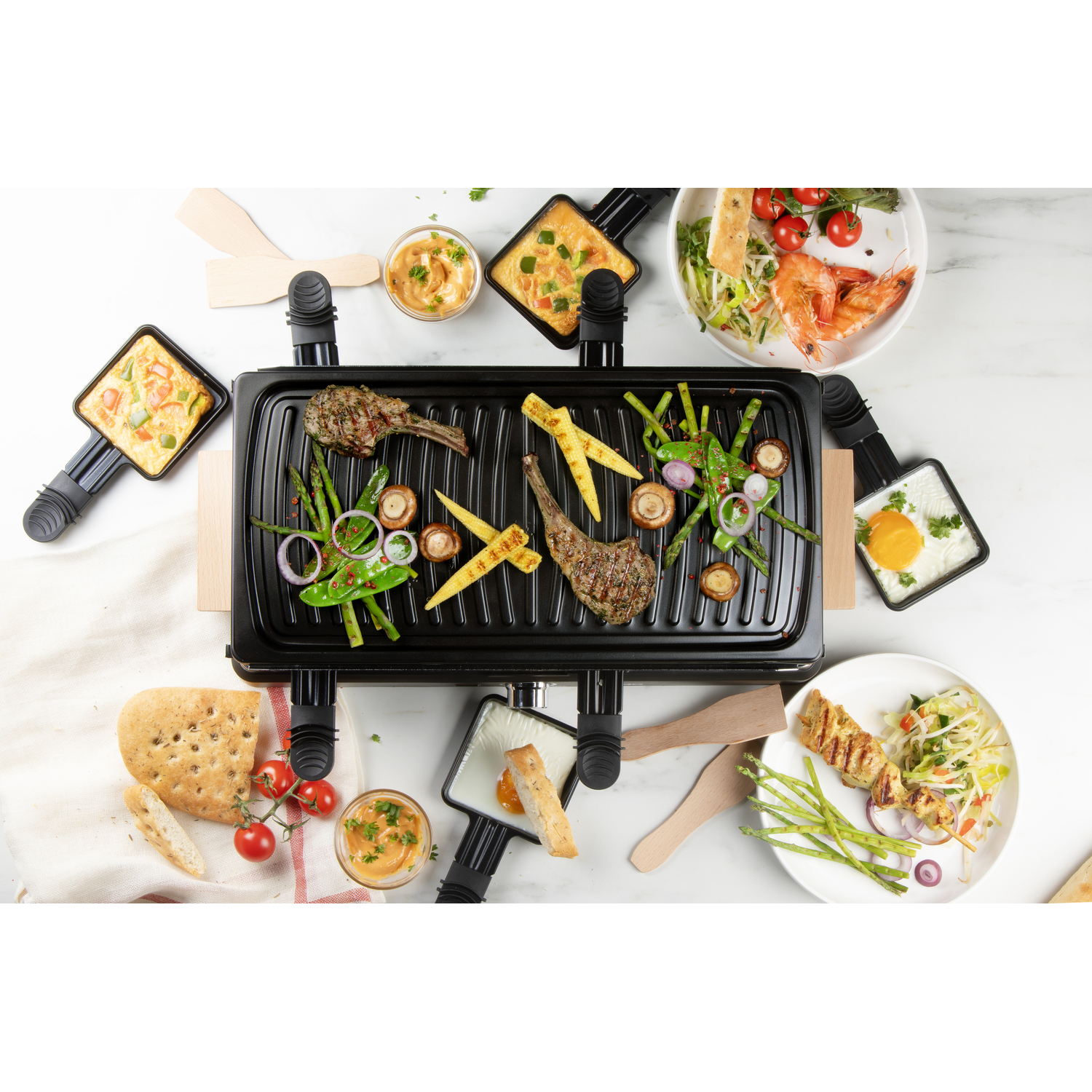 Un appareil à raclette avec des aliments et ingrédients cuits. Vue de dessus.