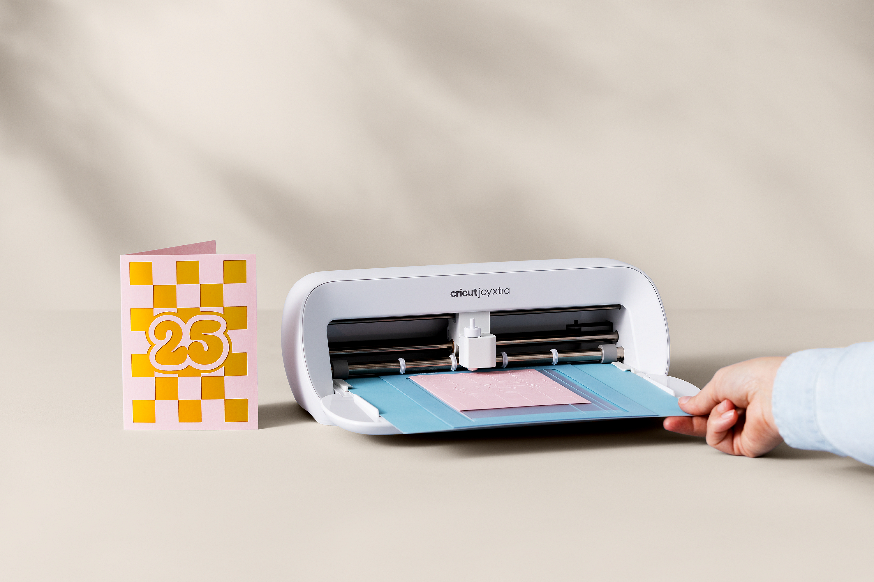 Cricut Joy Xtra Maschine mit Person, die Material einlegt, mit Karte.