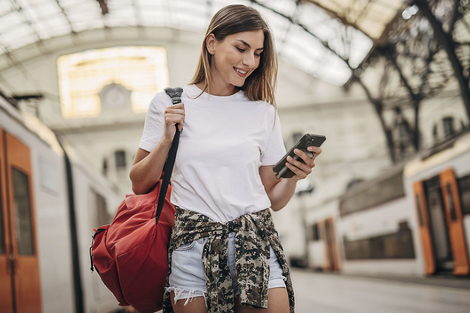 Una mujer en una estación de tren mirando su teléfono.