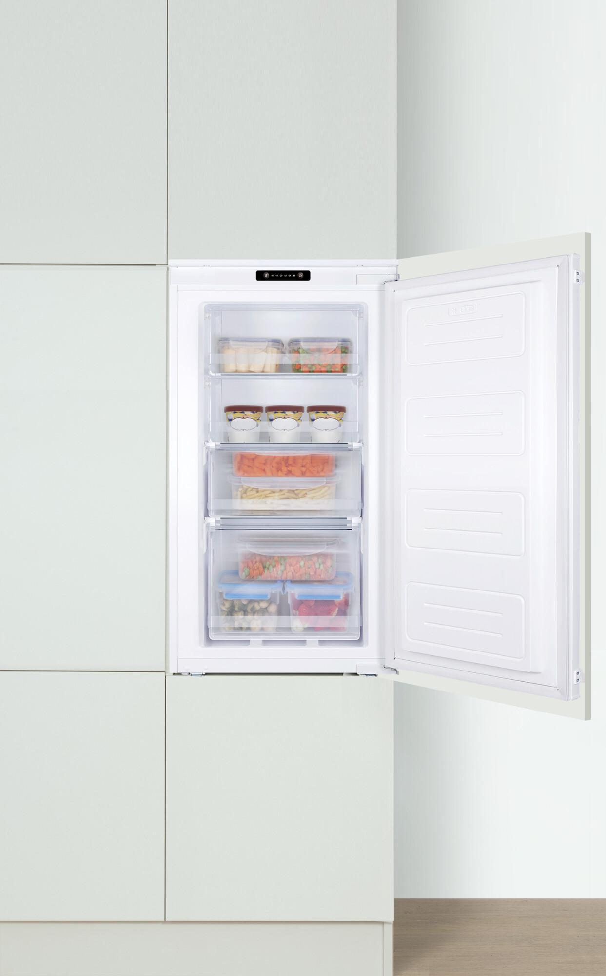 Ein eingebauter weißer Gefrierschrank mit offener Tür, der Schubladen mit Lebensmitteln zeigt.