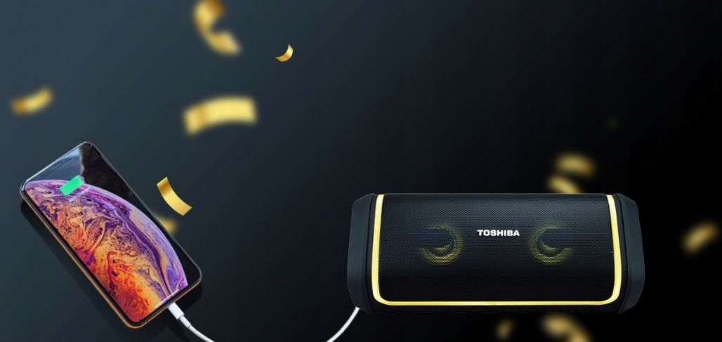 Telefon ładuje głośnik. Złote konfetti spada. Głośnik jest czarny ze złotymi akcentami.