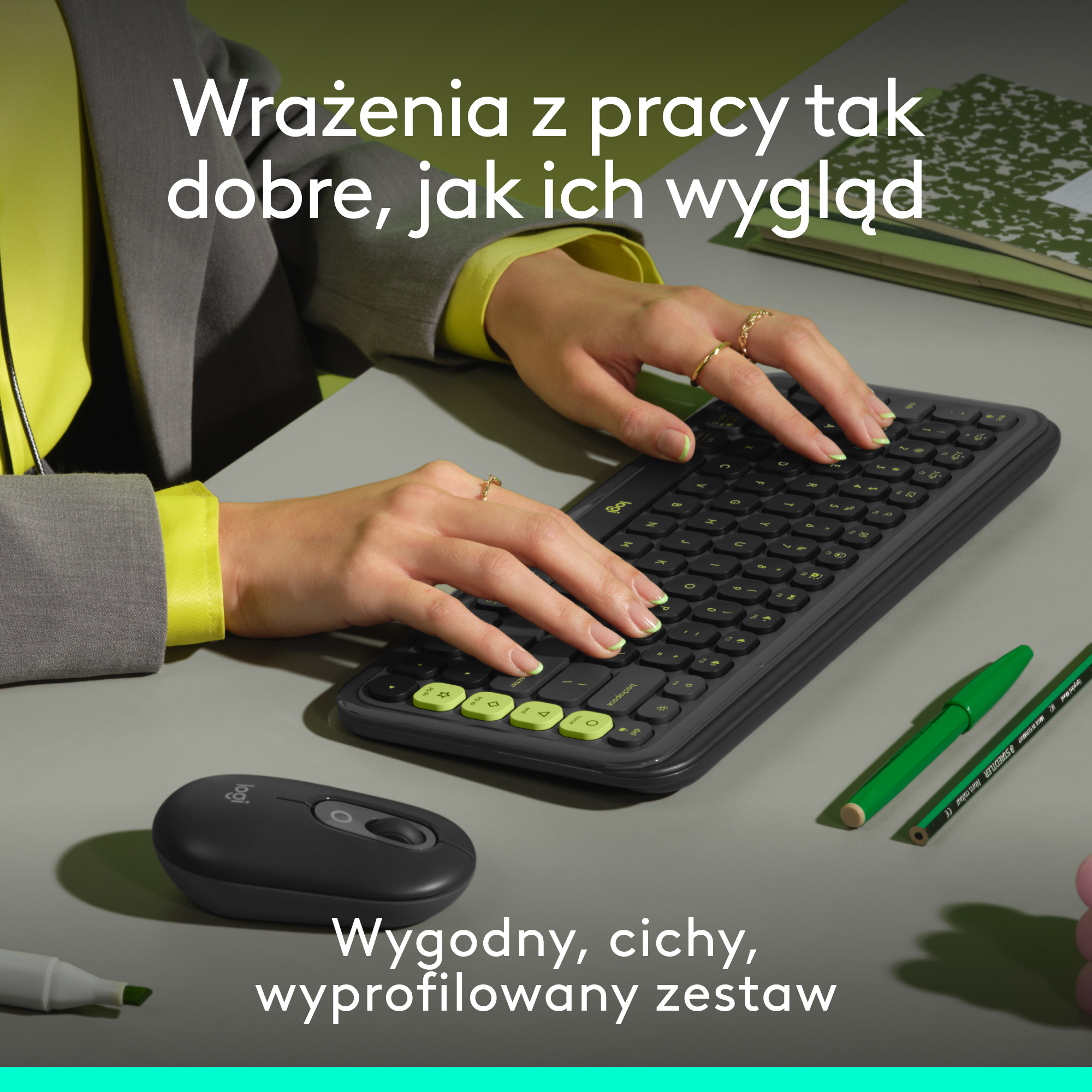 Osoba używająca czarnej klawiatury i myszy, z notatnikiem i zielonym długopisem na stole.