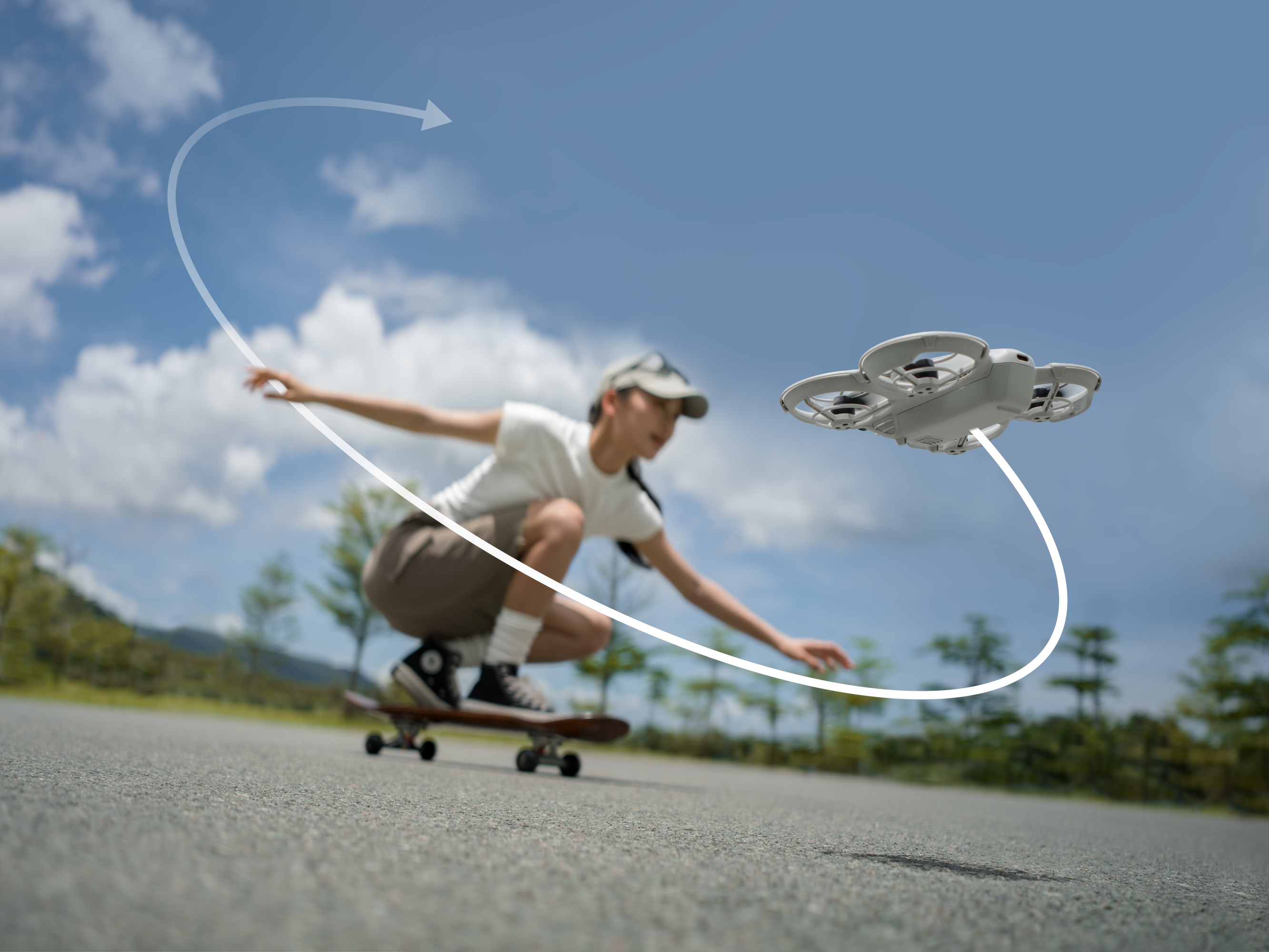 Une jeune femme faisant du skateboard avec un drone suivant une trajectoire de vol incurvée au-dessus.