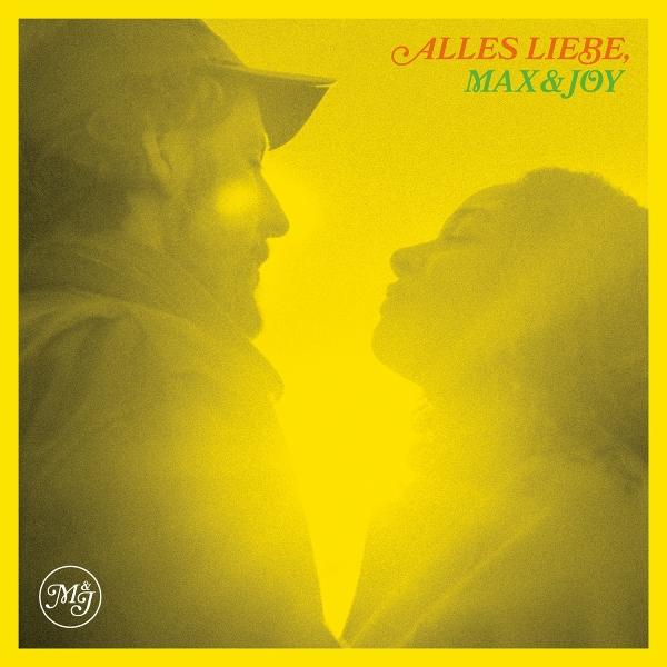 Ein gelbstichiges Bild von zwei Personen im Profil. Der Text oben lautet 'Alles Liebe, Max & Joy'.