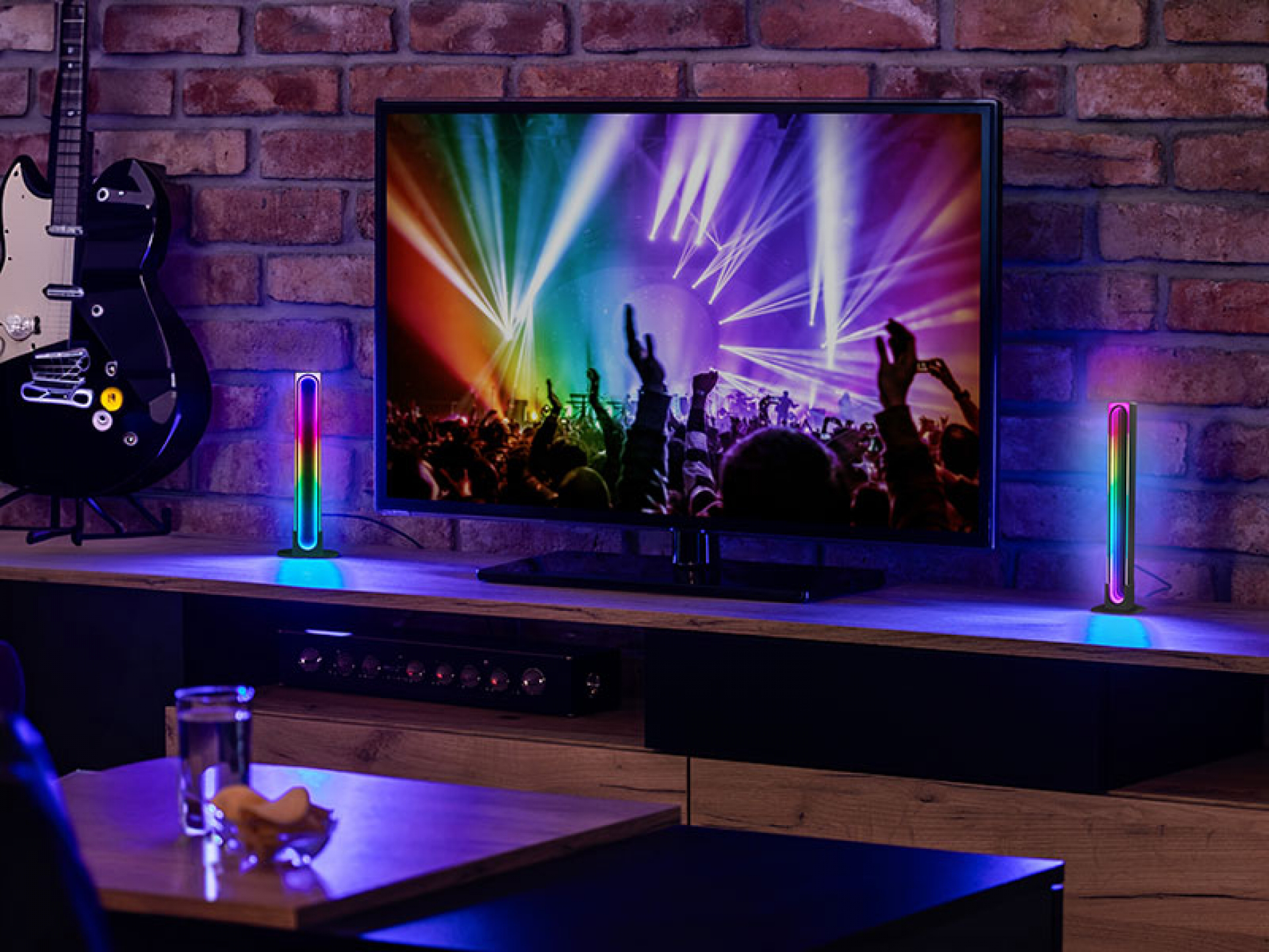 TV színes koncertjelenetet mutat. Két RGB fénysáv az asztalon.