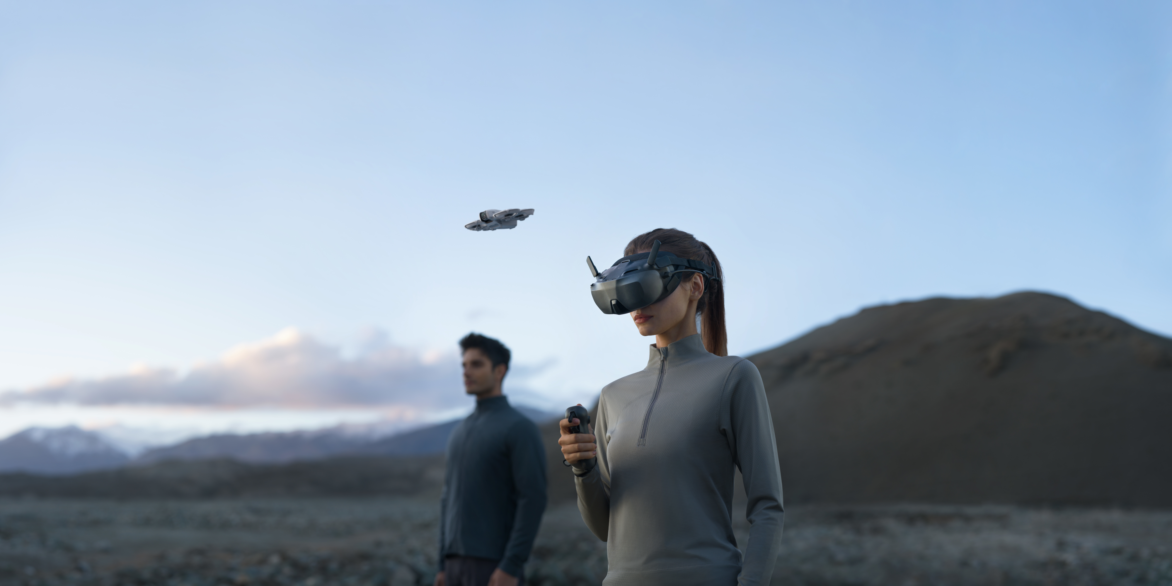 Femme avec casque VR, manette, et drone volant dans le ciel.