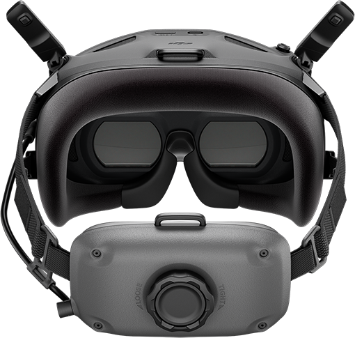 Egy fekete VR-headset és egy szürke akkumulátorcsomag közelképe egy tárcsával. A headset két szemlencsével és fejpánttal rendelkezik.
