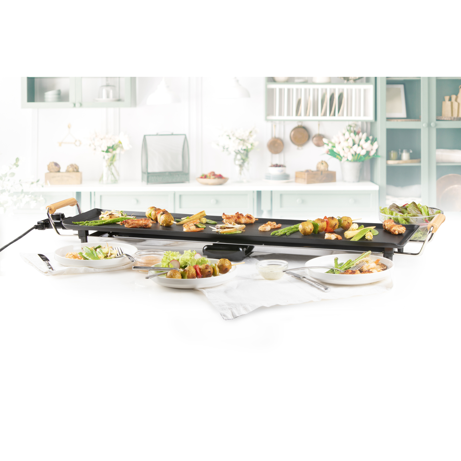 Une table avec des aliments grillés et des assiettes. La table est dressée pour un repas avec des brochettes et des légumes.