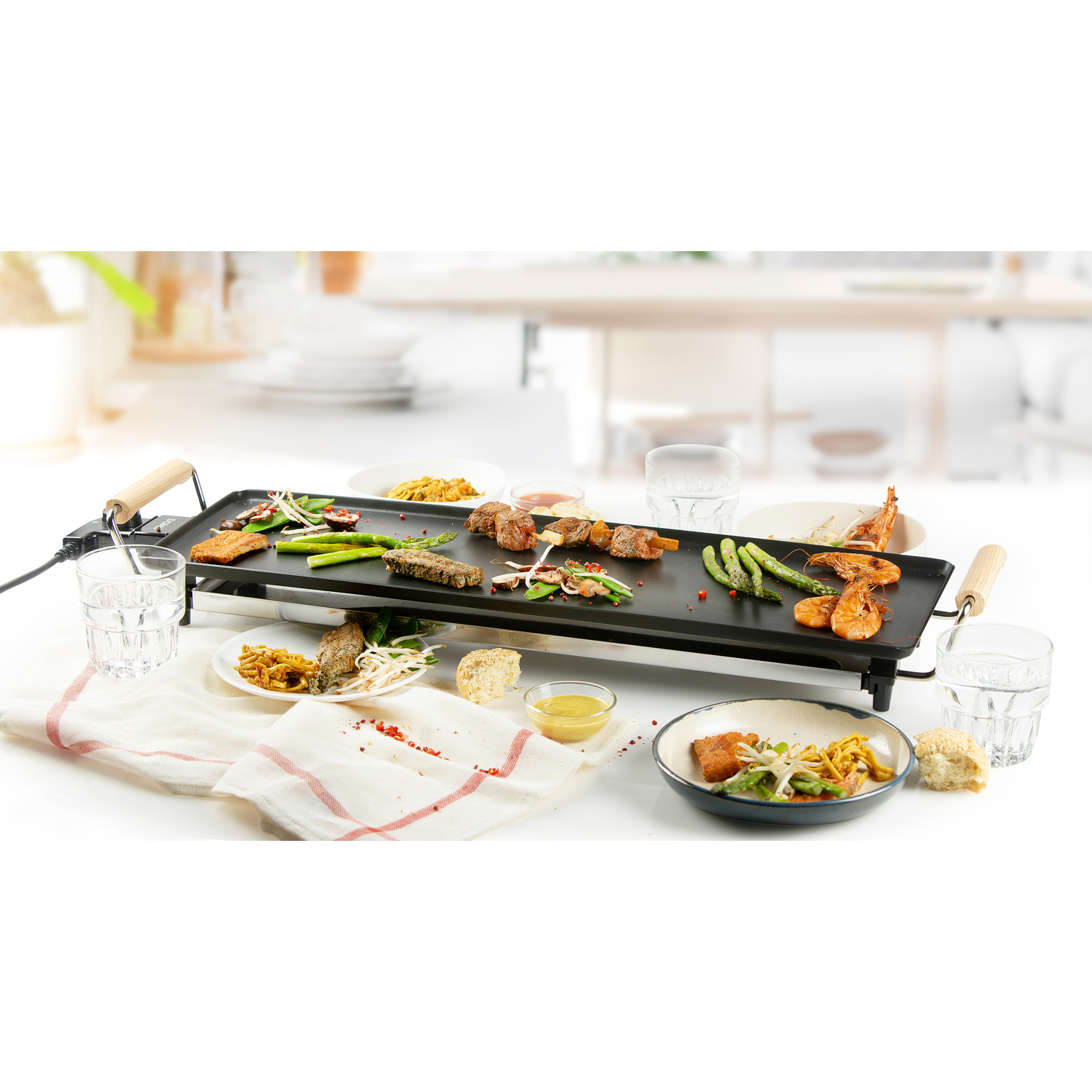 Tafel met gegrild eten, borden en glazen. Wit tafelkleed en neutrale achtergrond.