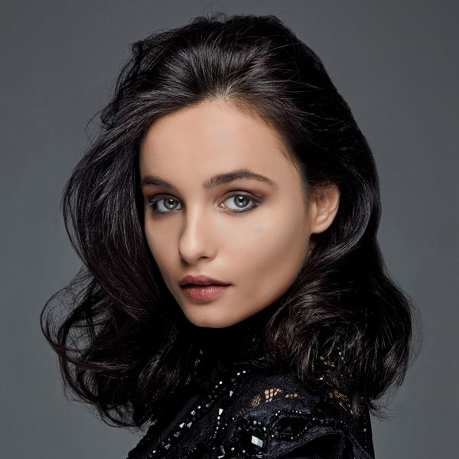 A woman with dark hair and a black top. She has a neutral expression.