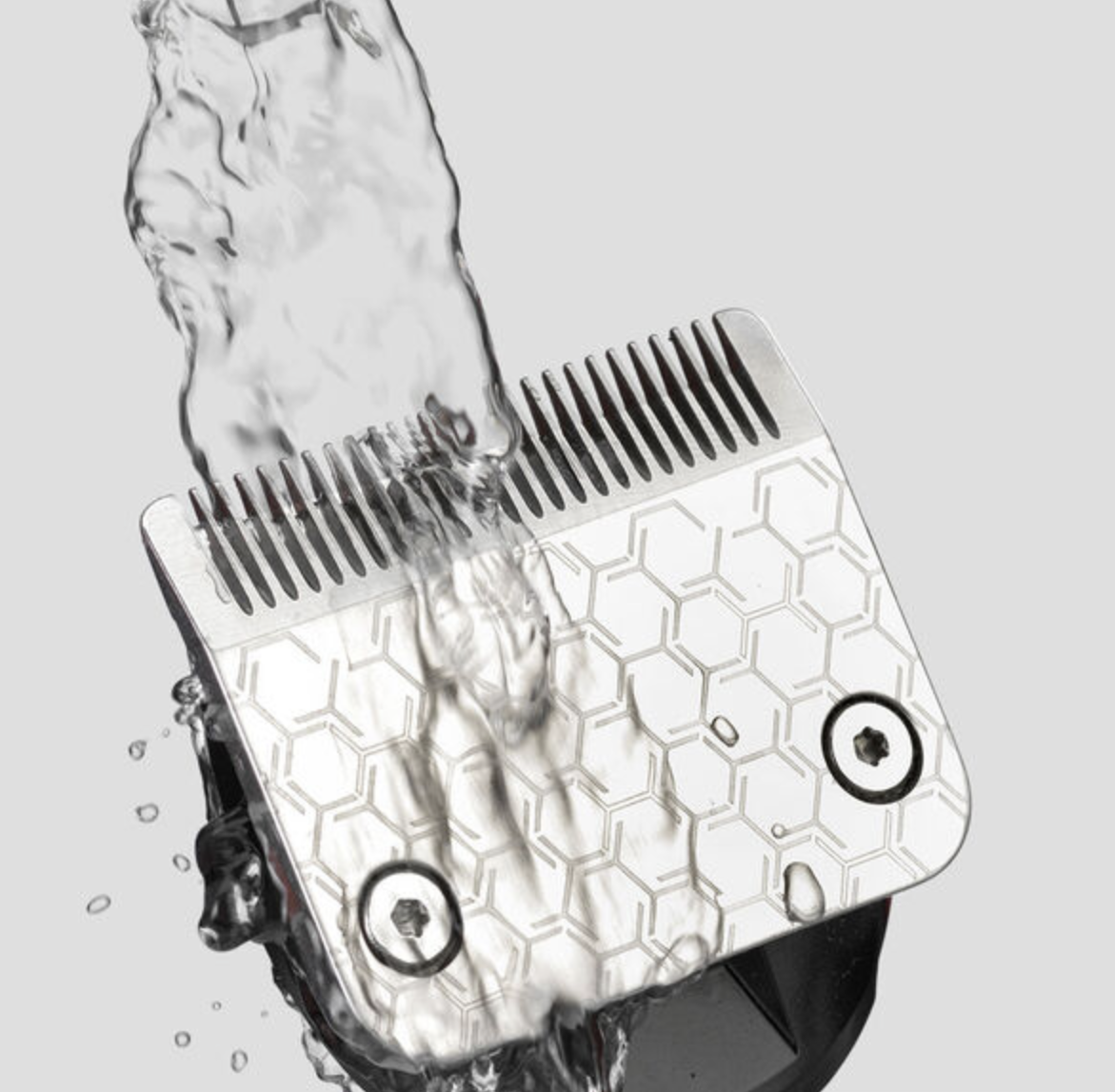 Nahaufnahme einer silbernen Haarschneidemaschinenklinge, die mit Wasser gespült wird.