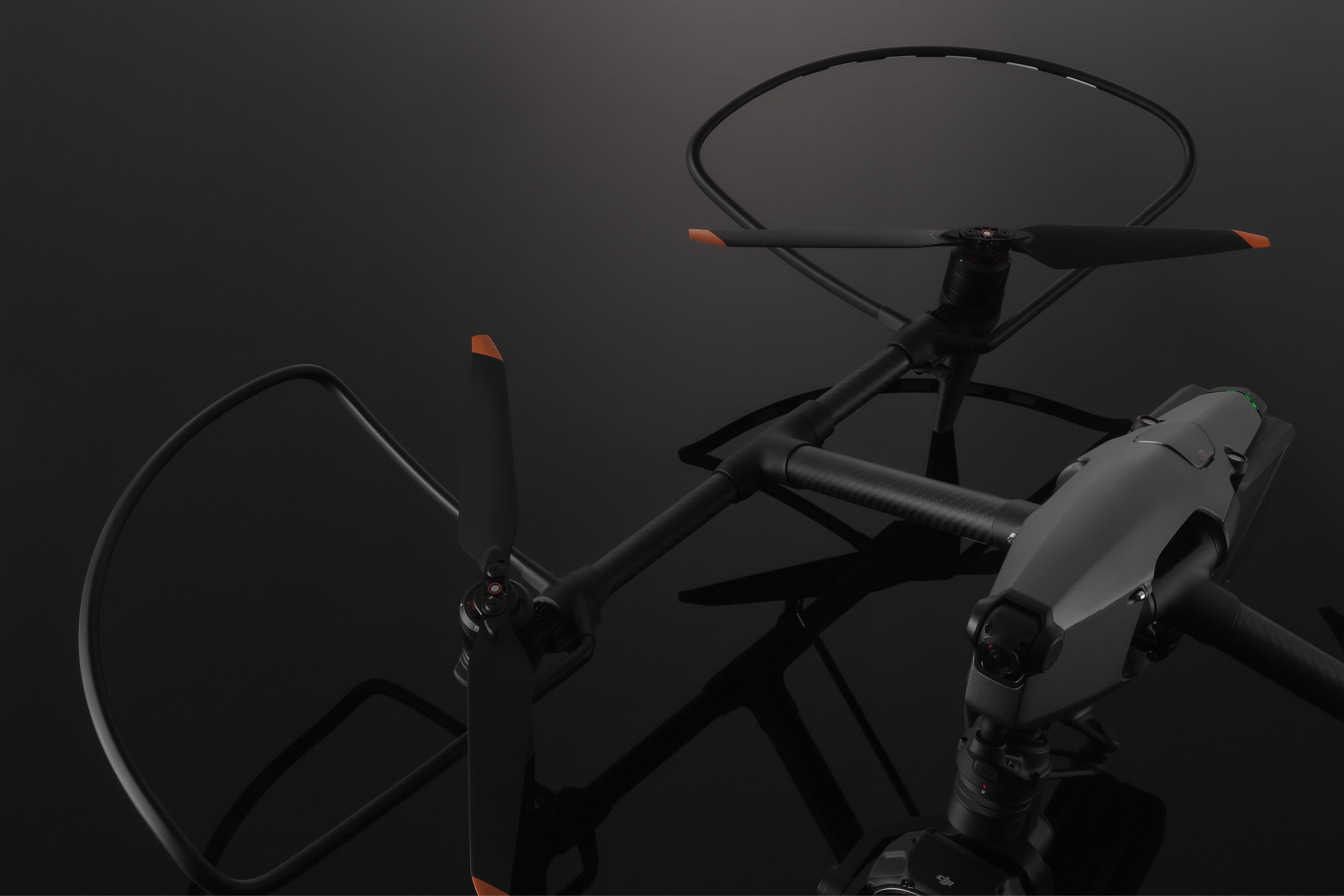 Schwarze Drohne mit orangefarbenen Akzenten. Die Propeller sind auffällig mit dunklem Hintergrund.