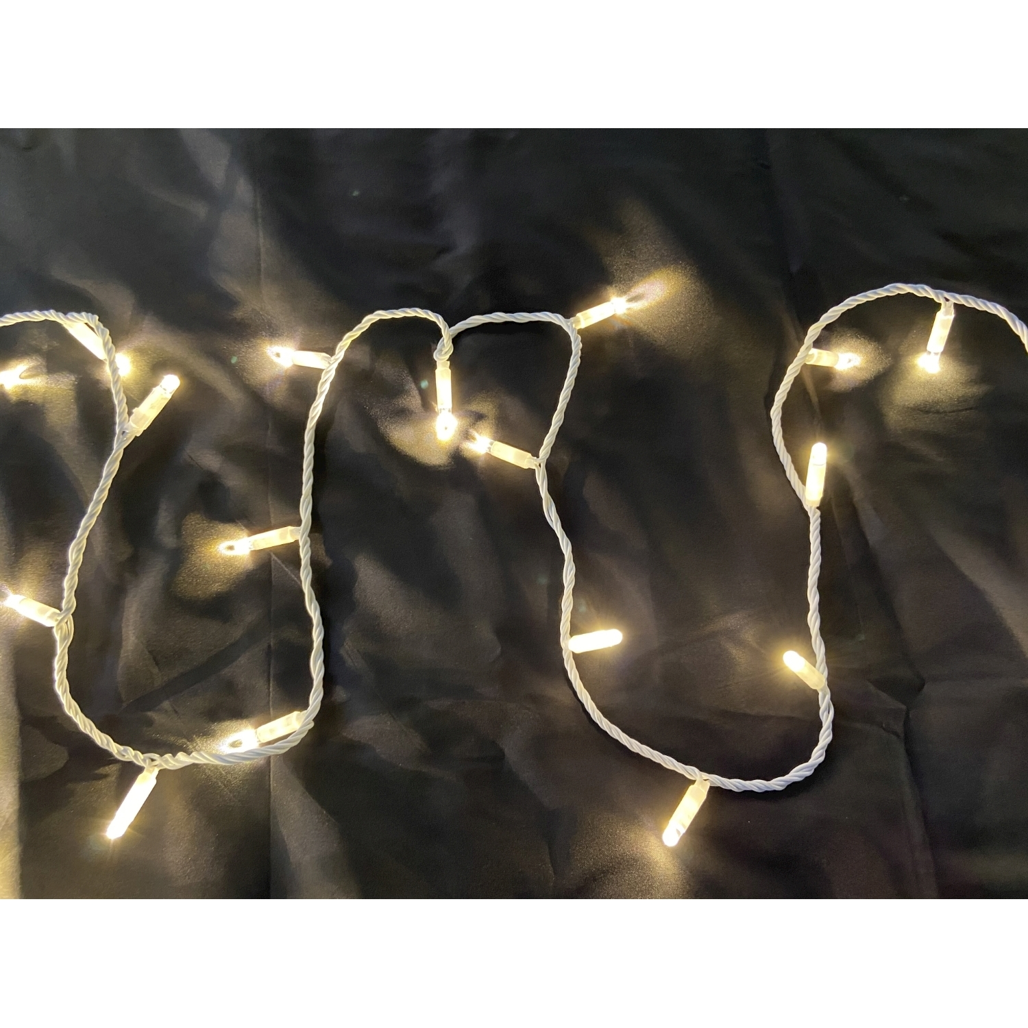 Luci a corda bianche calde su una superficie nera. Le luci sono accese e creano un effetto brillante.