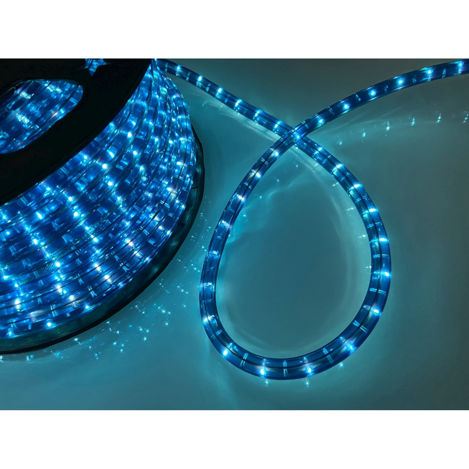 Strisce luminose a LED blu arrotolate su una bobina nera. Sfondo bianco. Bagliore blu chiaro.
