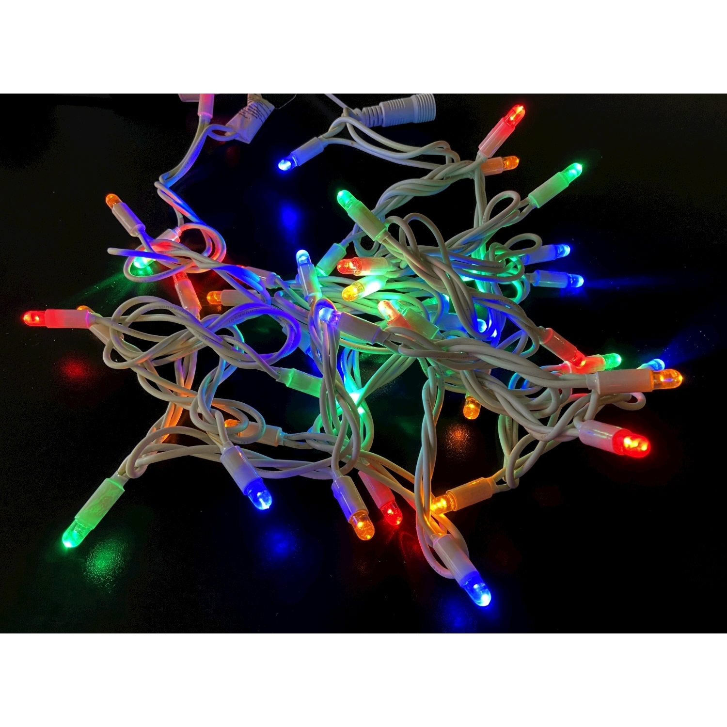 Luci di Natale multicolori aggrovigliate su una superficie nera.