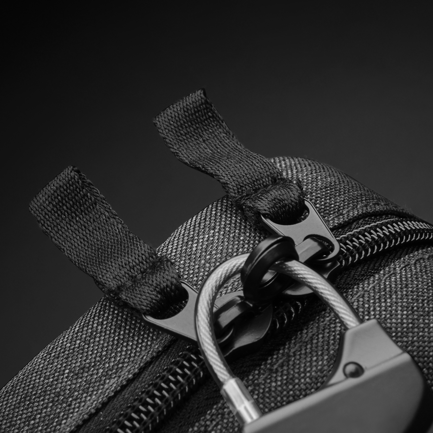 A black bag with a lock, close-up view of the lock and zipper.